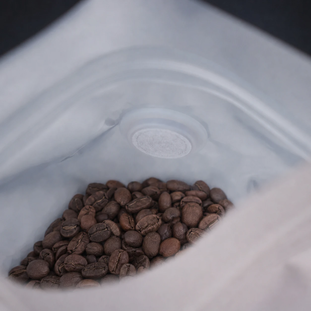 Inside a real coffee pouch containing roasted beans, with the inner film and one-way valve visible